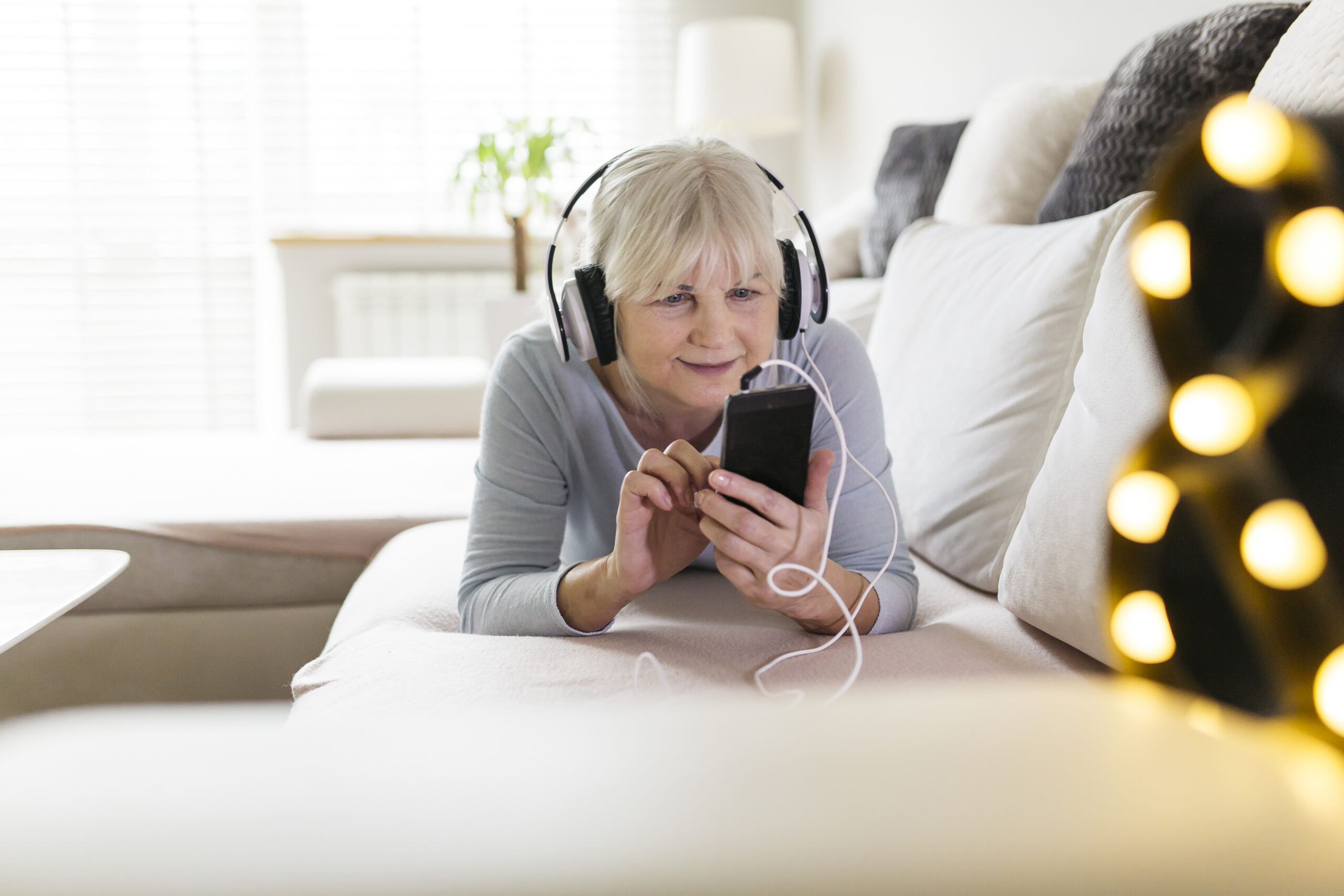 oudere dame geniet van muziek op haar 50+ mobiele telefoon